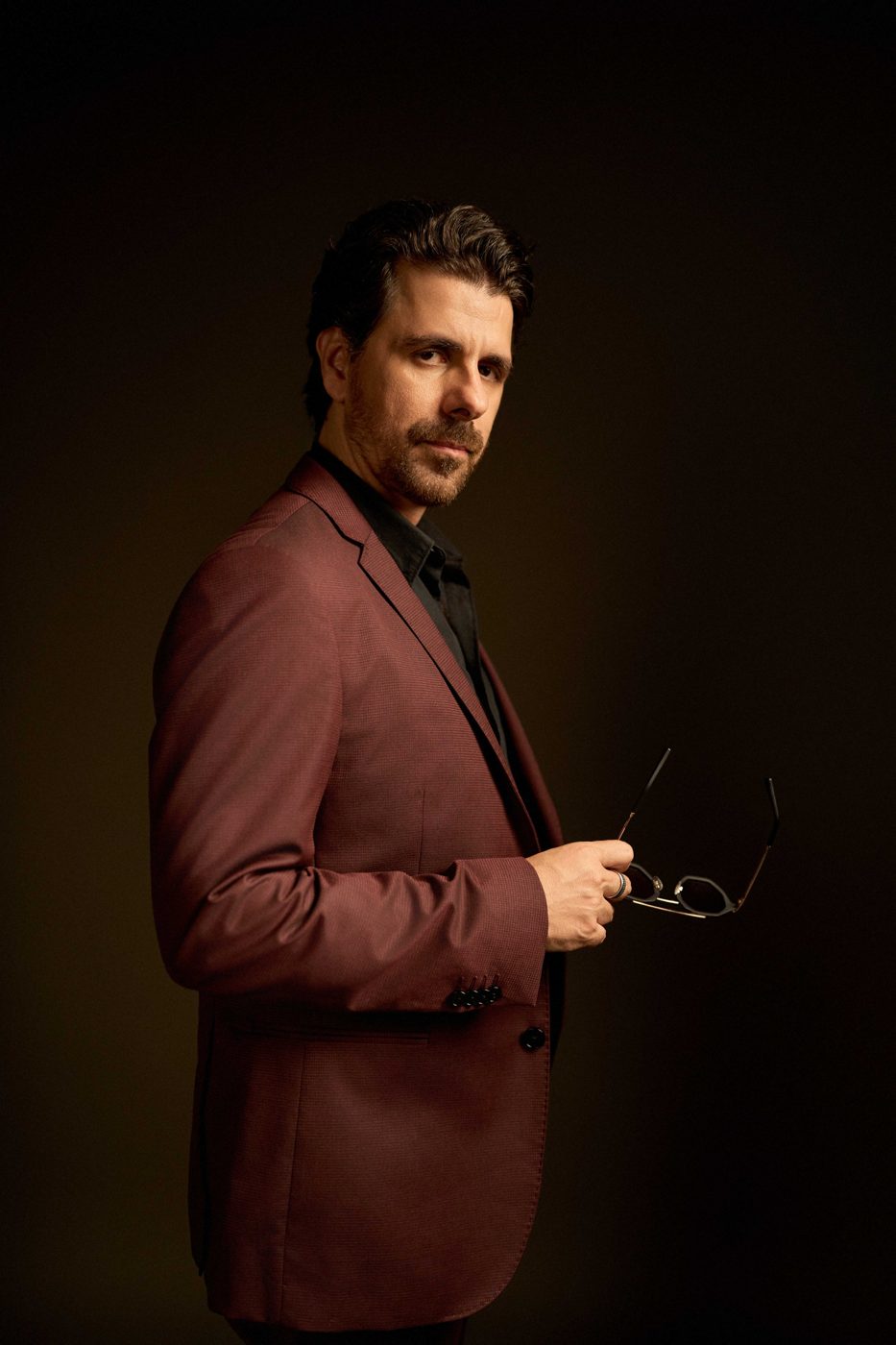 Rui Simas com óculos na mão, retrato de estúdio
